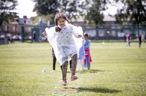 Asian child poncho hopping through hoop Asian child poncho hopping through hoop